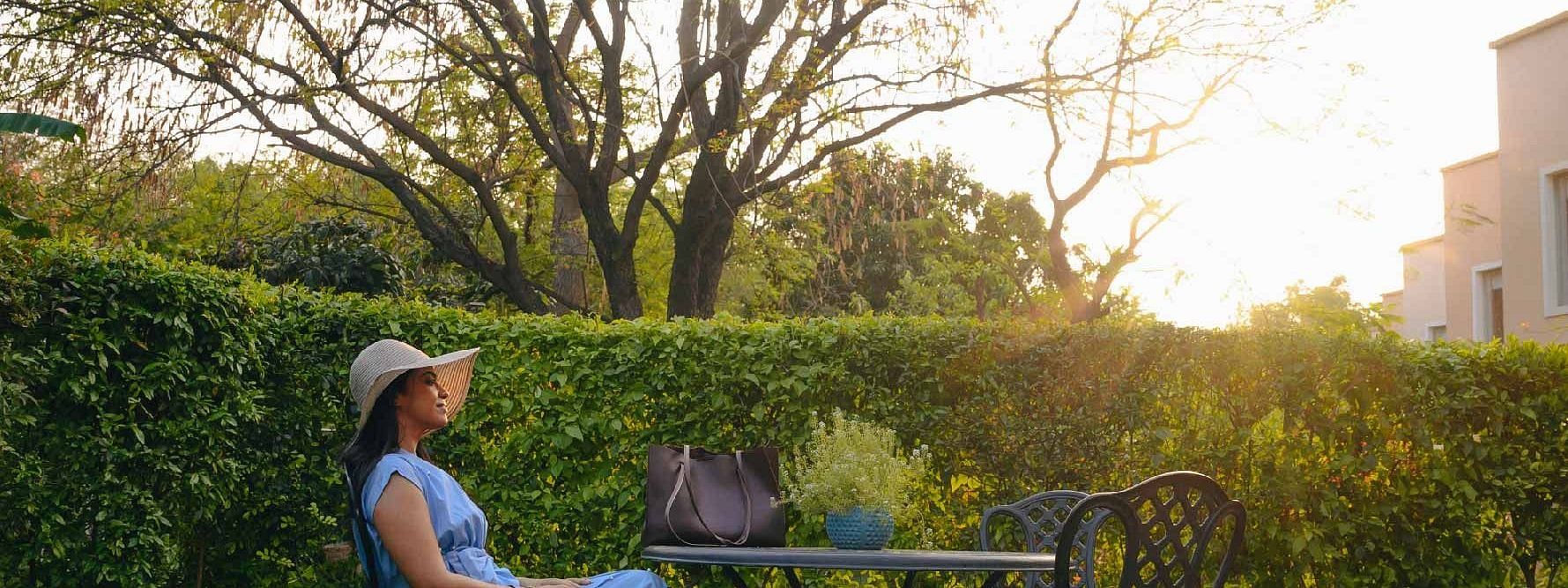 Guest seated at a black metal table set in the garden during sunset at Karma Chalets.