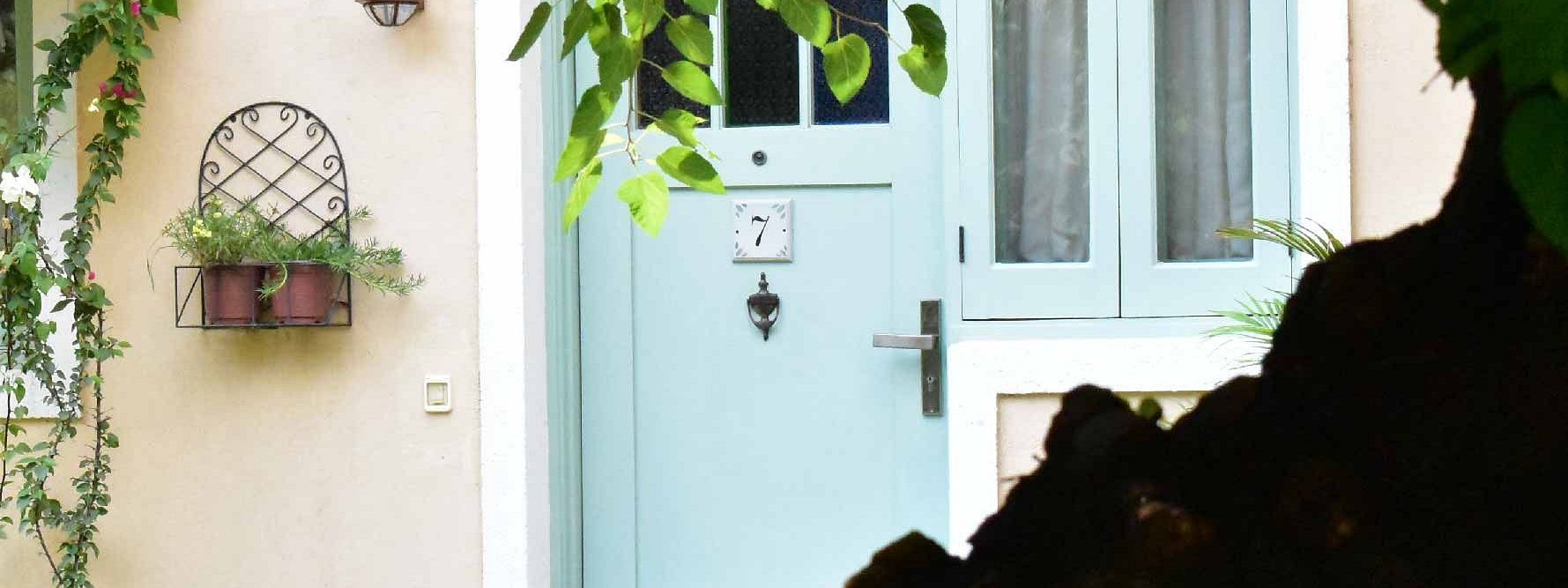 View of a light blue door and vine-covered entrance of a cottage at Karma Chalets.