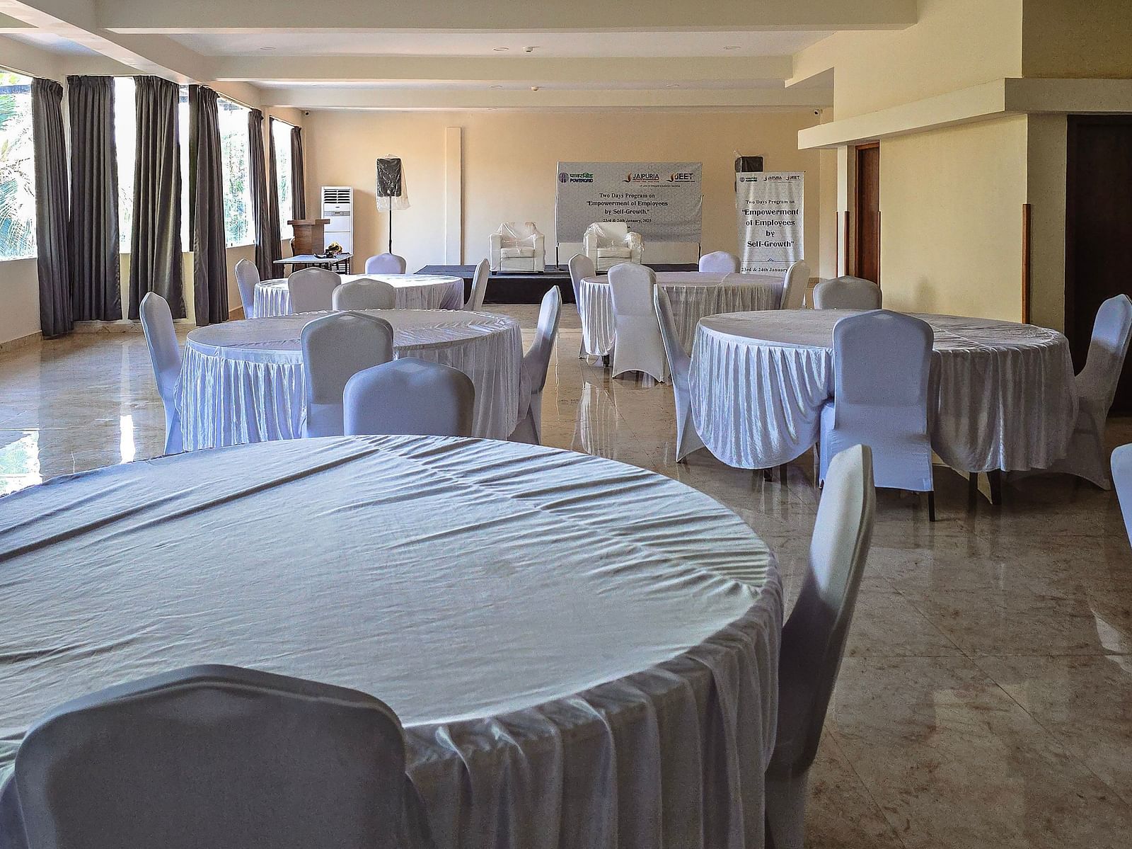 Event space set up with white-covered round tables and natural lighting at The Verda de Miranda Resort.