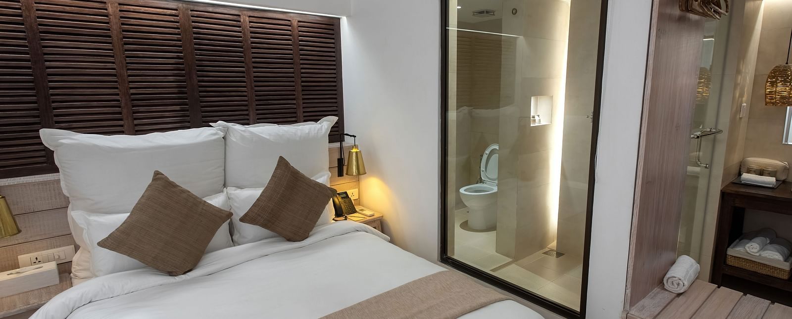 Standard room with a bed, bed side table, lamps and the washroom area - The Nanee