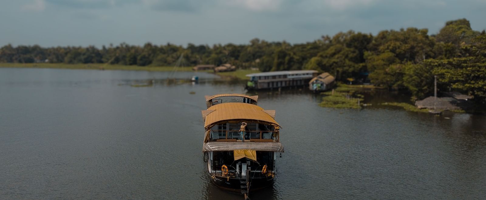 A cruise sailing across the Vembanad Lake with lush greenery in the background - BluSalzz Villas - Muhamma Resort, Alleppey