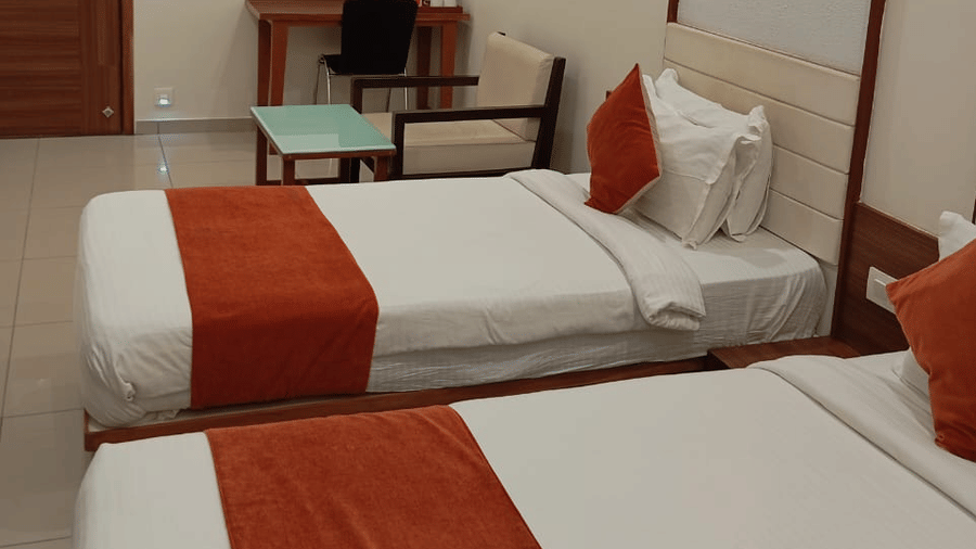 A Deluxe Twin Room at Hotel Ashray Inn Express showcasing twin beds, seating area, mounted television, and neatly arranged interiors.