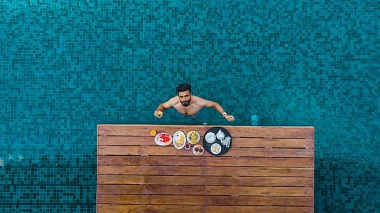 aerial shot of a man enjoying his food and drinks in the swimming pool - Symphony Samudra Beachside Jungle Resort And Spa, Port Blair