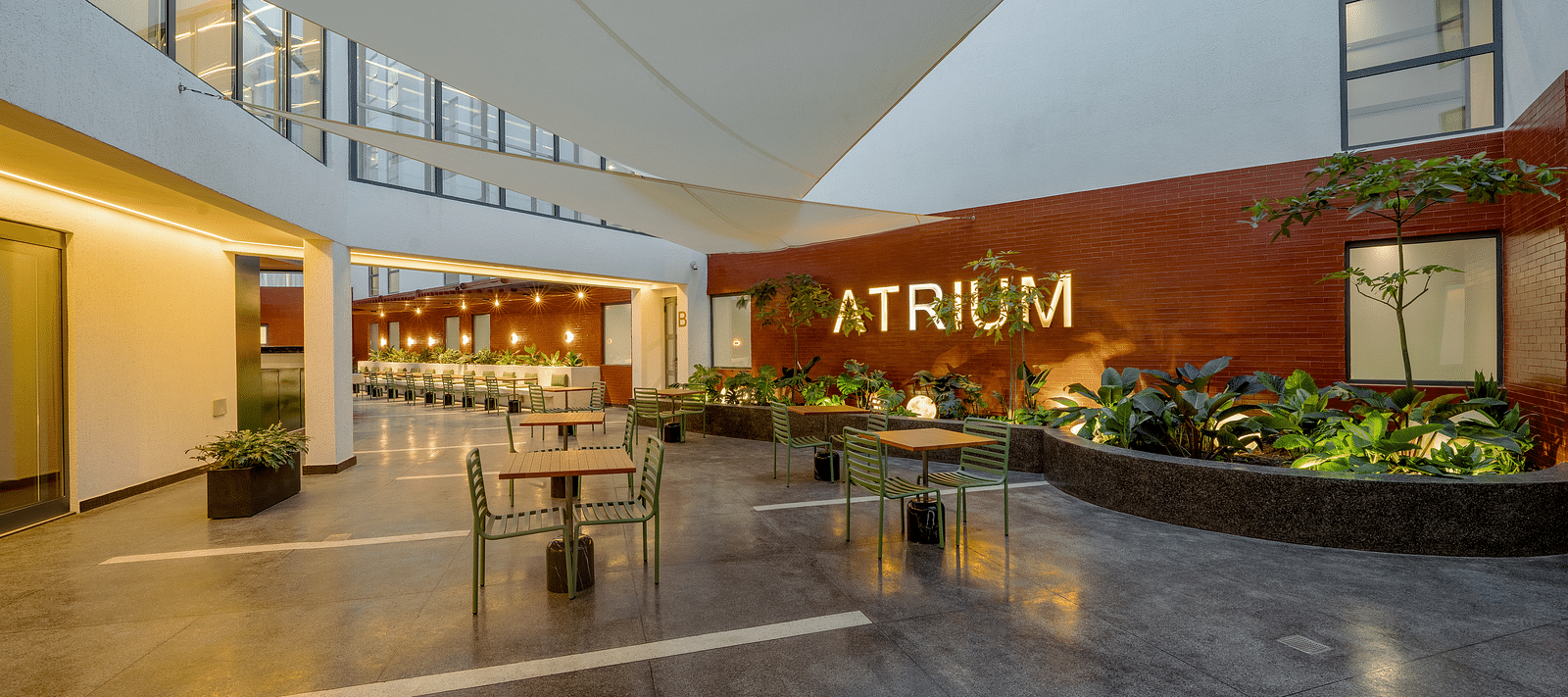 A modern outdoor seating area with a large, red 'ATRIUM' sign on the wall.  - The Pelican Hotel, Accra