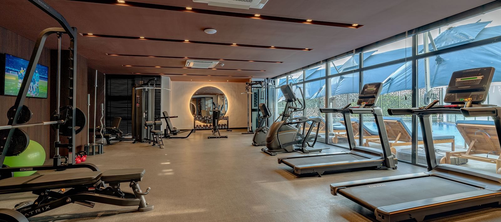 Bright, spacious gym with treadmills and weight machines lining the window wall. - The Pelican Hotel, Accra
