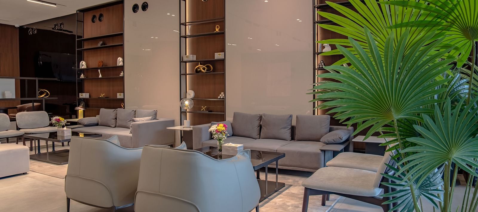 A well-lit living room with large windows, a variety of seating options, and potted plants.