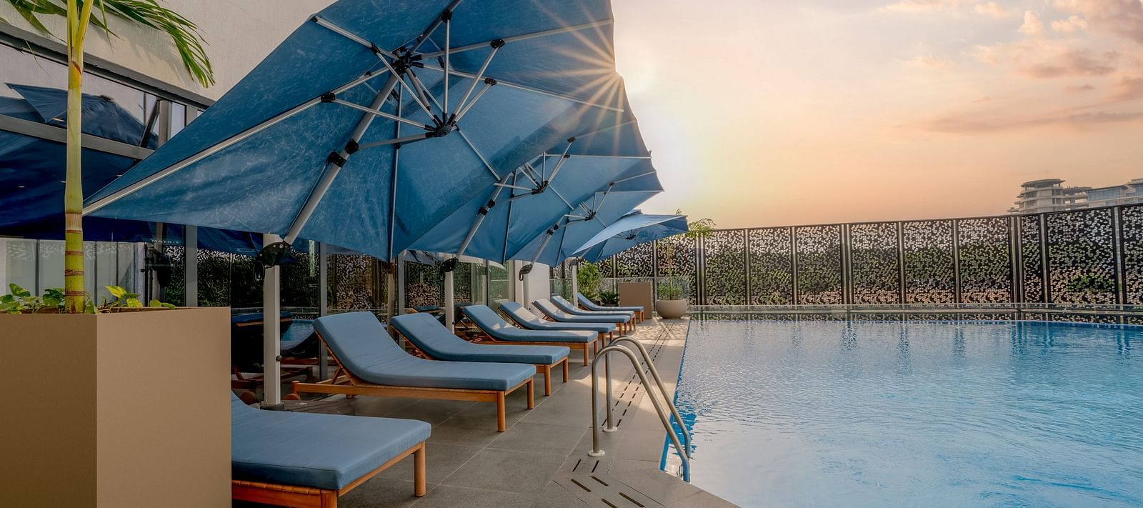 A pristine swimming pool glistens under a warm sunset sky, inviting a refreshing dip. - The Pelican Hotel, Accra