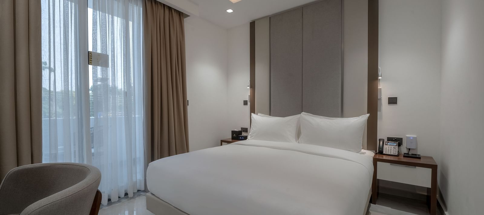 A modern Junior Suite with a large king size bed near a large window. - The Pelican Hotel, Accra