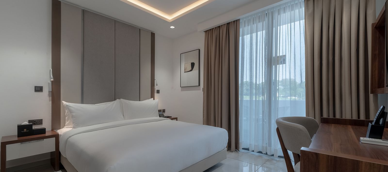 Spacious Standard Room with king size bed, soft lighting, wooden desk, large window, and cozy ambience. - The Pelican Hotel, Accra