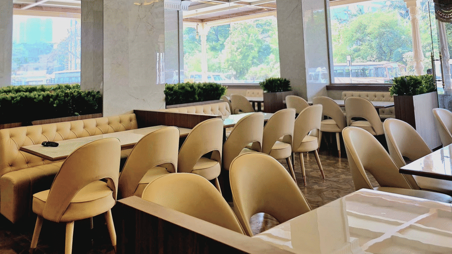Bright dining area with modern seating and large windows at Hotel Mumbai House, Digha, Airoli.