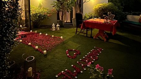 Garden setup with tables, chairs, and rose petals arranged for an outdoor evening celebration beside a house at Karma Chalets. 