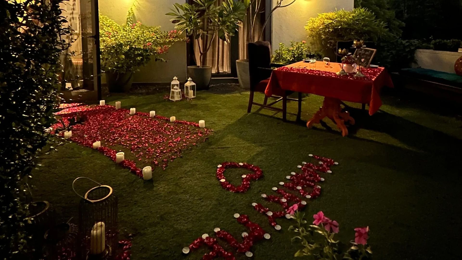 Garden setup with tables, chairs, and rose petals arranged for an outdoor evening celebration beside a house at Karma Chalets. 