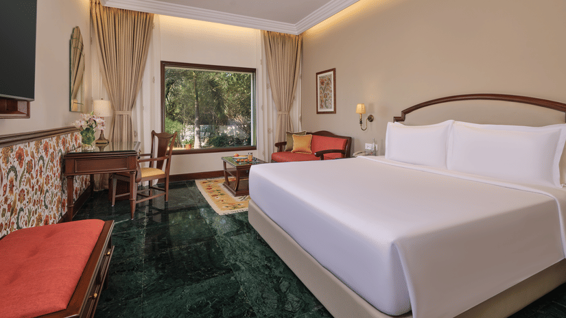 The Premium King Garden View Room at The Ummed Ahmedabad featuring a spacious interior with warm lighting and a king size bed facing the TV mounted on the wall