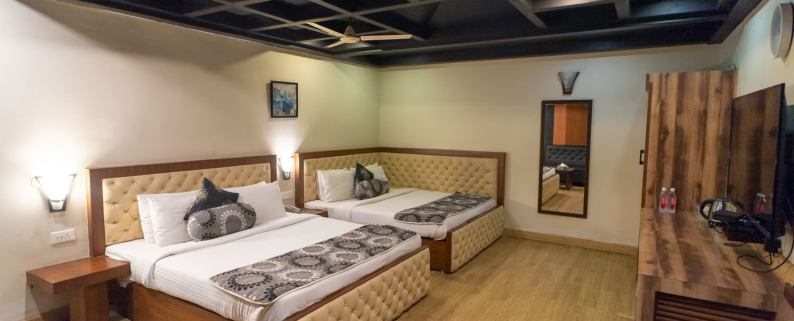 Family Room featuring two large beds, desk, and wooden wall paneling. - Hotel Ashok Nagpur