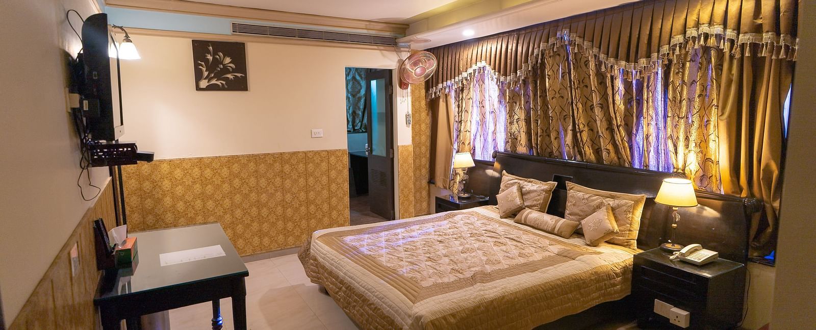 Queen Room featuring a bed, a desk, and a television. - Hotel Ashok Nagpur