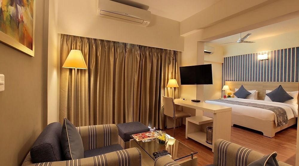 Deluxe room at Starlit Suites, Bangalore with a double bed and sofa seating