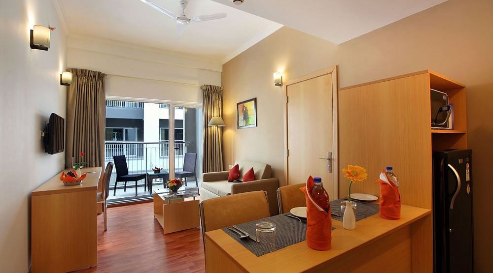 Overview of the living room inside Deluxe One Bedroom Suite - A double bed with side tables and lamps inside Deluxe Room - Starlit Suites, Kochi