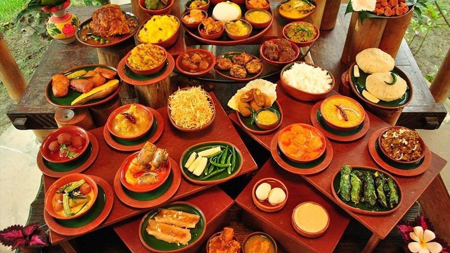 A large spread of various Indian dishes in small clay pots arranged on a table | Vedic Village Spa Resort, Kolkata