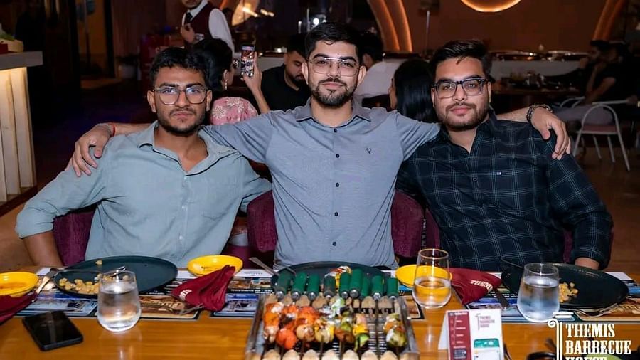 Guests posing for a photo with a spread of barbecue food in front at Themis Barbecue House, Ambala