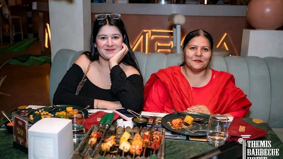 Guests posing for a photo with a spread of barbecue food in front at Themis Barbecue House, Ambala
