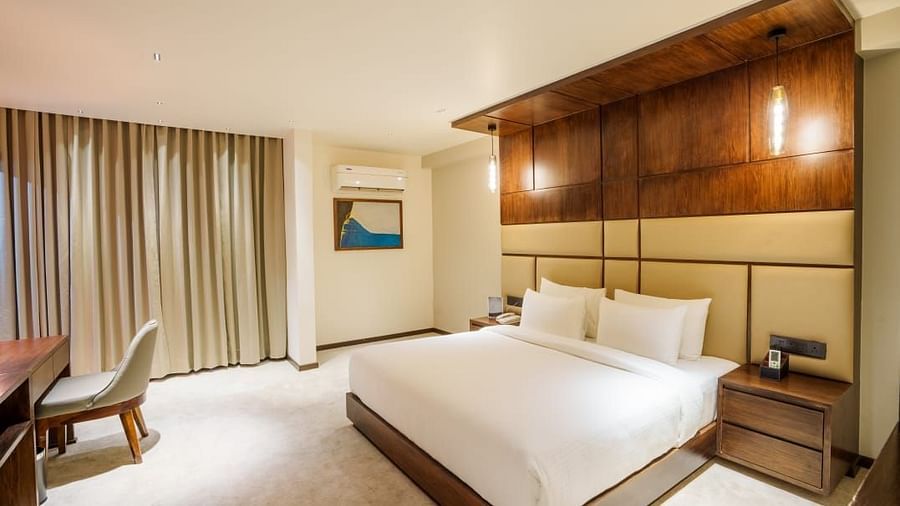 A image of a room with a comfortable bed, warm lighting and furniture for added comfort and usability