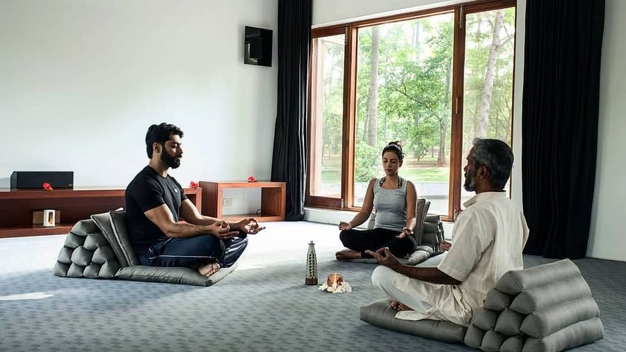 A couple participating in Trataka meditation along with a yoga teacher in a closed yoga space - Shreyas Retreat