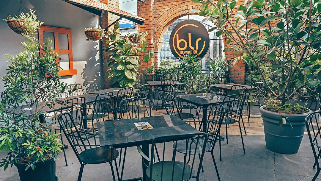 Outdoor patio seating area of TBLR Brewing Co, featuring black metal tables and chairs.