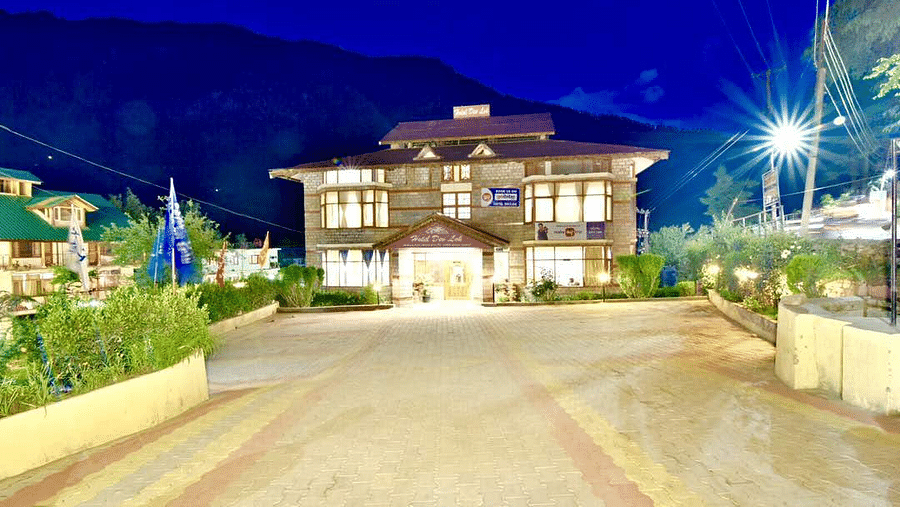 A view of the facade of DLS Hotel Devlok, Manali with the mountains in the backdrop at night