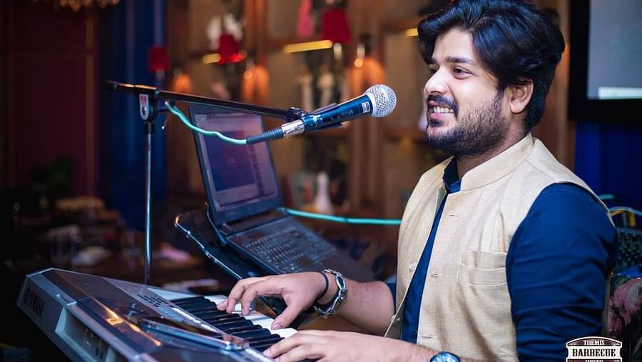 An image of a man singing and playing a piano at the same time - Themis Barbecue House, NSP Pitampura