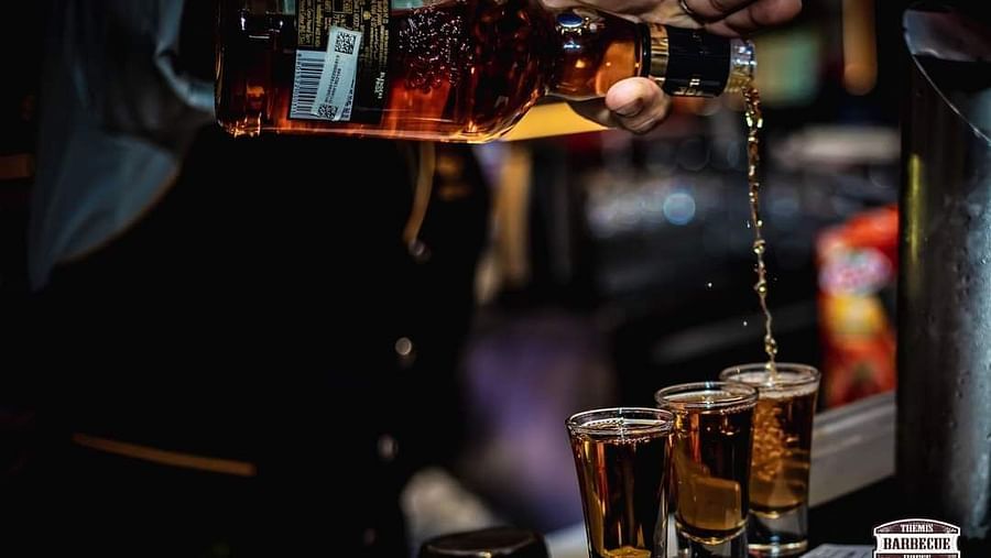 An image of a person pouring drink on a glass at Themis Barbecue House, NSP Pitampura