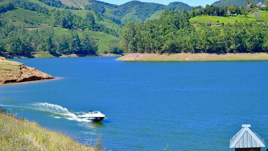 Boating area on a lake with mountains surrounding it and a boat gliding by the shore