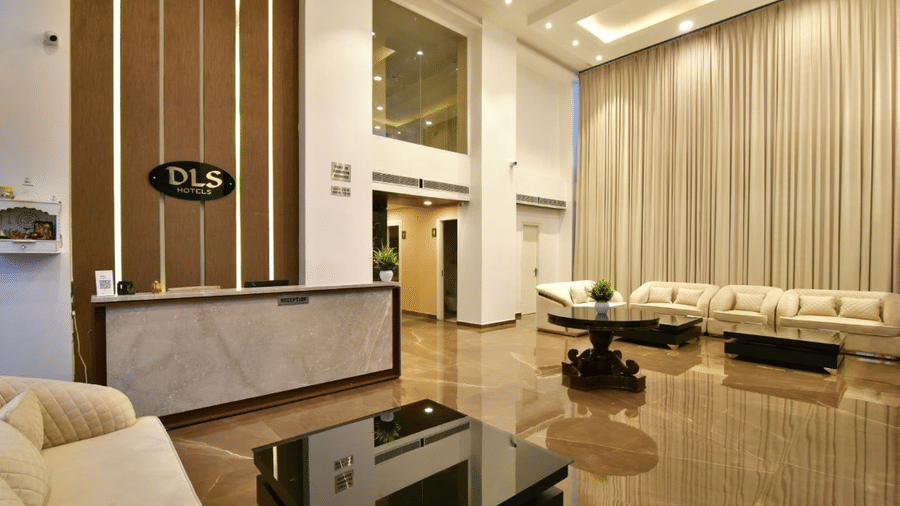 Front desk and lobby area with beige sofas, glass coffee table, and warm ambient lighting at Claret Inn, Dalhousie.