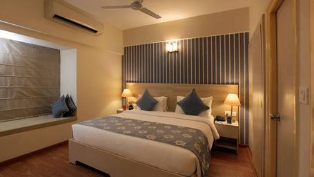Deluxe room at Starlit Suites, Bangalore with a double bed and side tables