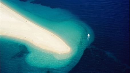 An aerial shot of an extended sand bar protruding to the deep blue waters. 