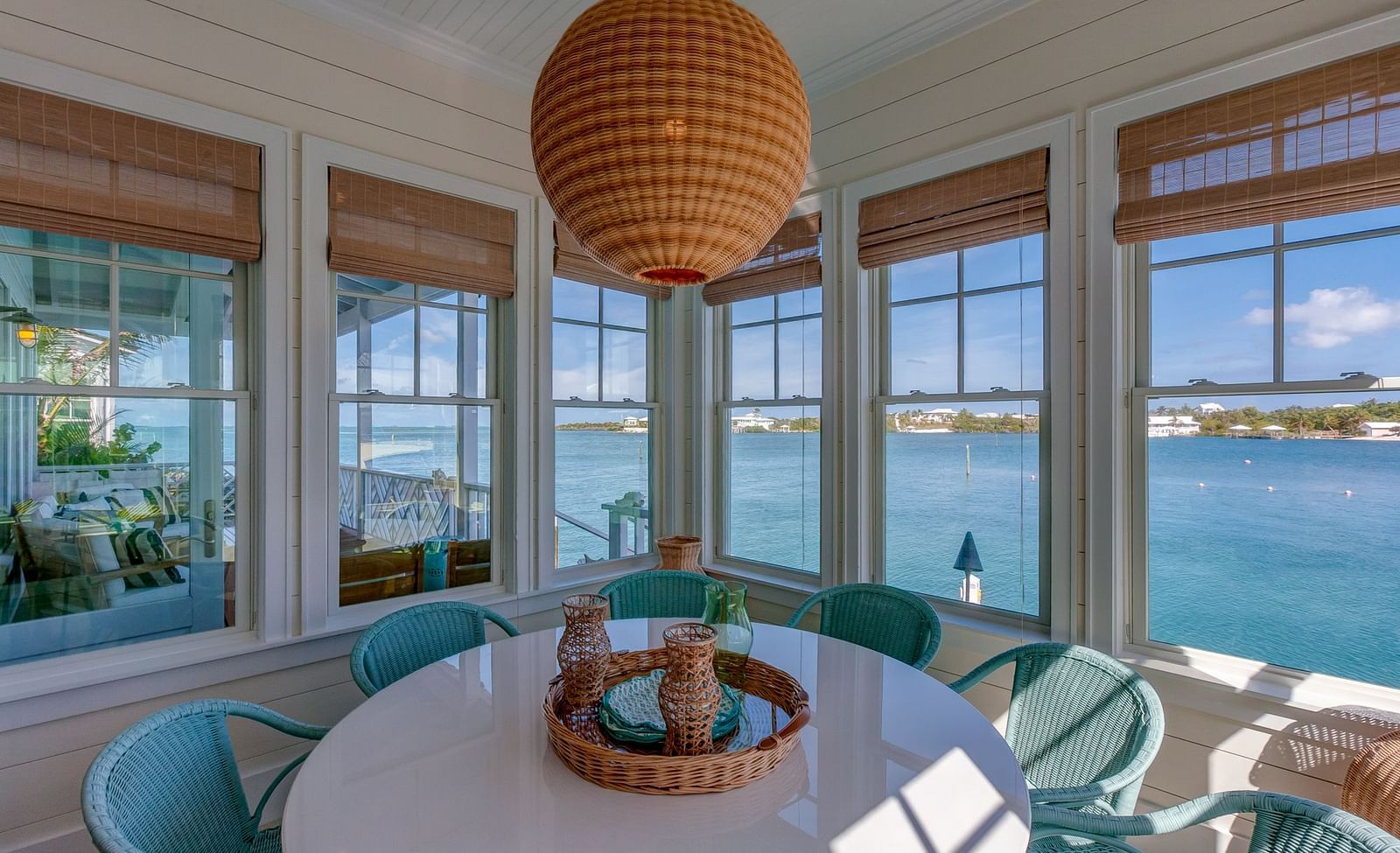Dining area with a round table, wicker pendant light, and large windows overlooking the water | Abaco Inn