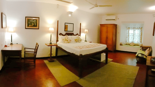 The Tower House - a beautiful room with queen size bed, a couch, a workdesk and in-room amenities. this room also features a window area with pristine white walls in the room
