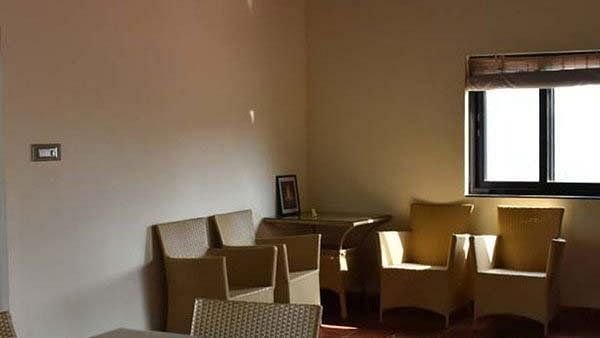 A room with tan walls, tan chairs, and a window with a dark frame
