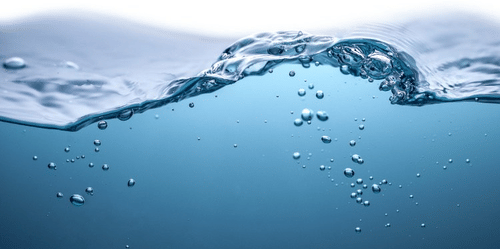 Water surface with rising bubbles creating movement across the frame, showing the upper layer shifting as air passes through from below.