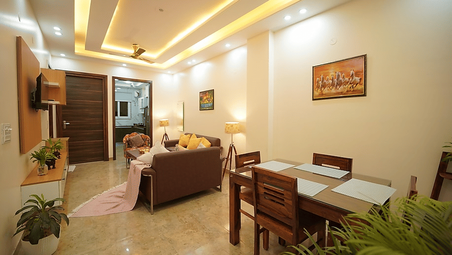 Dining and lounge area of Lime Tree Hotels & Service Apartment Private Limited featuring a dining table, seating, and potted plants.