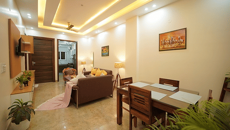 Dining and lounge area of Lime Tree Hotels & Service Apartment Private Limited featuring a dining table, seating, and potted plants.
