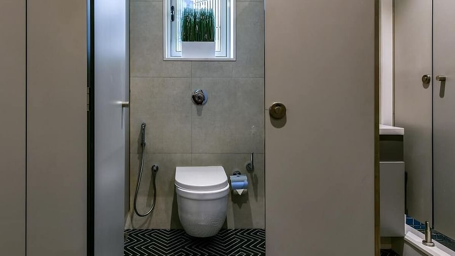 A spacious washroom entrance with a sliding door pulled to the side, leading to a western toilet at the far end, at Indie Stays, BKC Kalina.