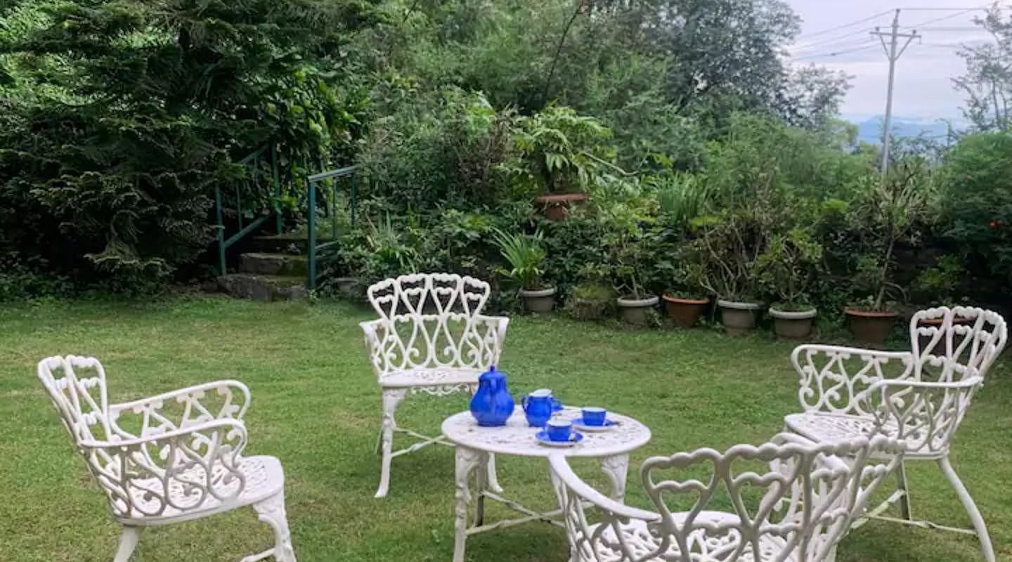A garden with lawn chairs around a table in 3 BHK at  in 3 BHK at SOUTHGATE KASAULI BY ZENQ.