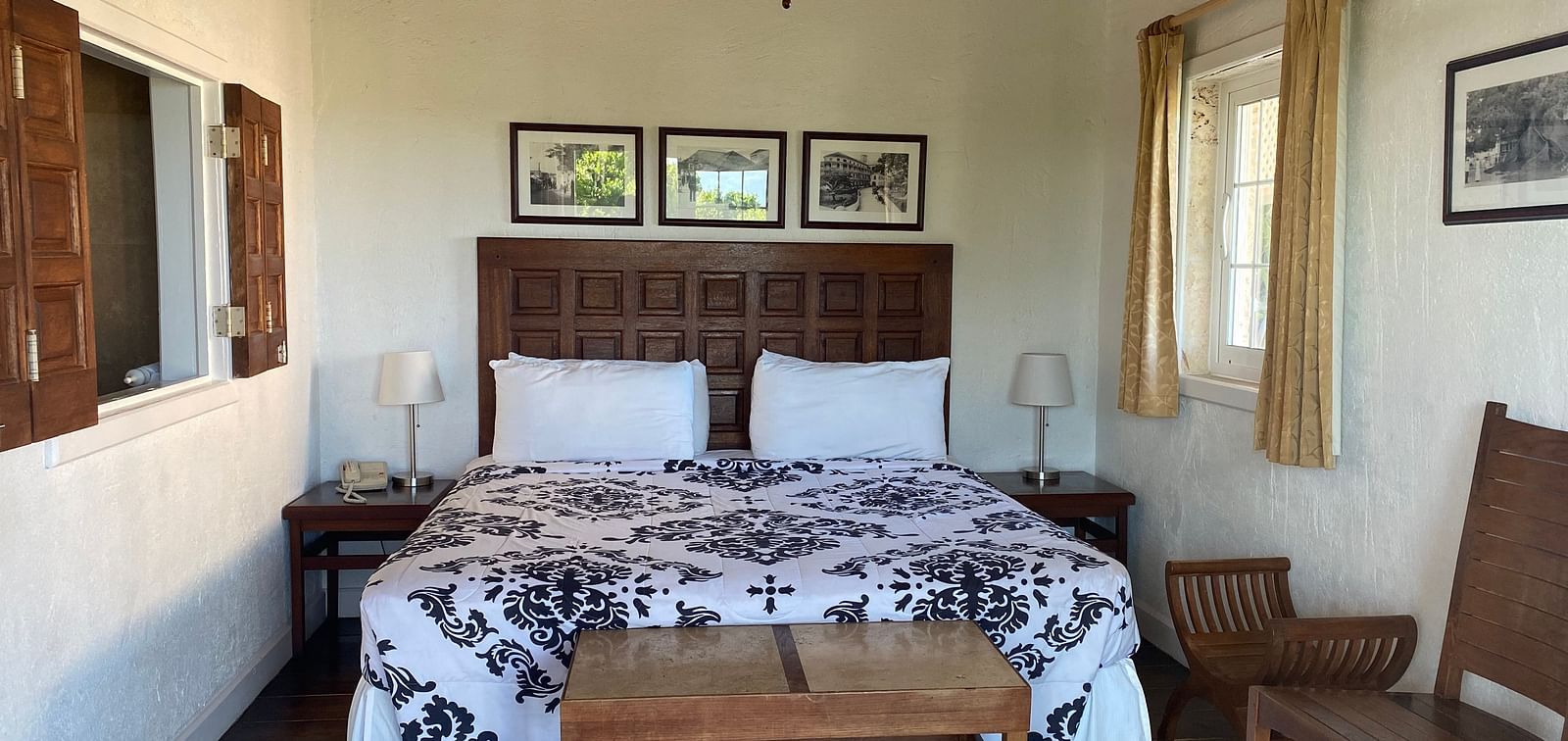 Bedroom with a large bed, ceiling fan, table, chair, and framed art on the wall | A Stone's Throw Away