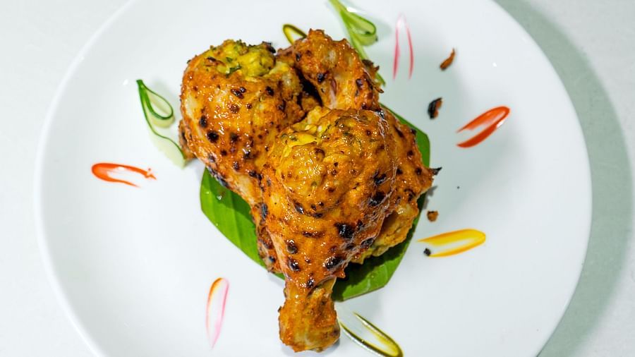 A plate with a piece of fried food, garnished with green sauce and herbs.