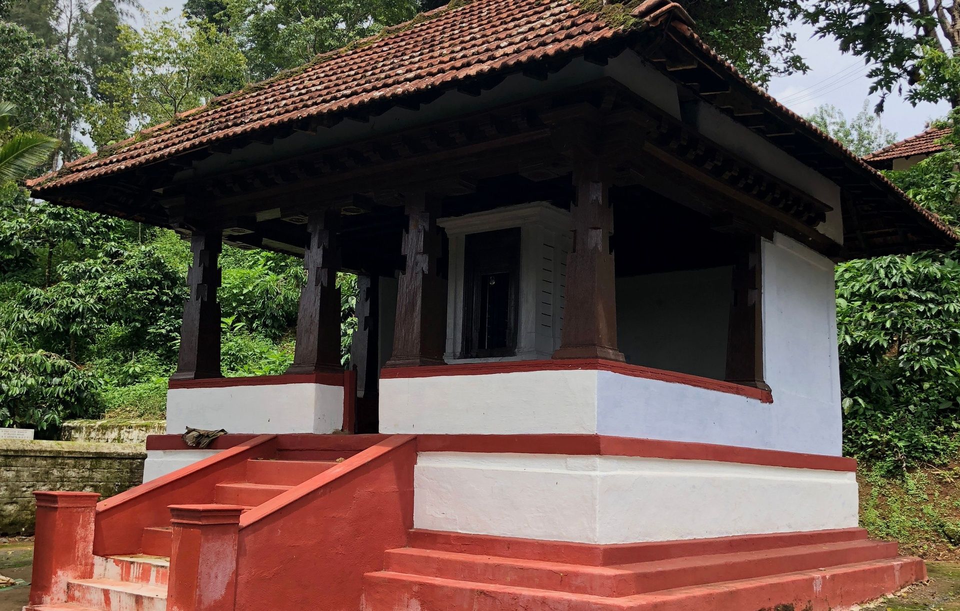 Kaimada shrine with red steps and tiled roof in Kodagu.