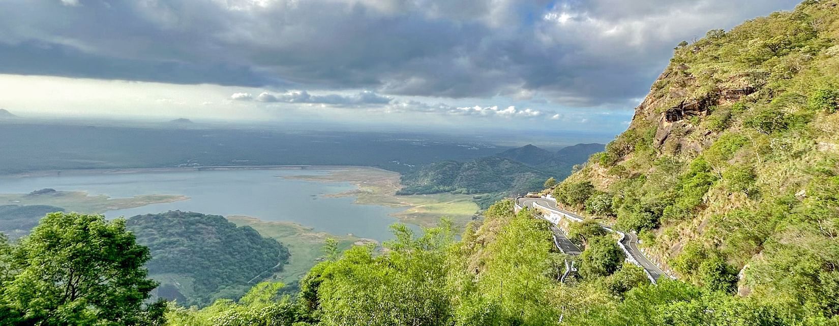 A view from the hilltop overlooking the lake with white clouds in the sky