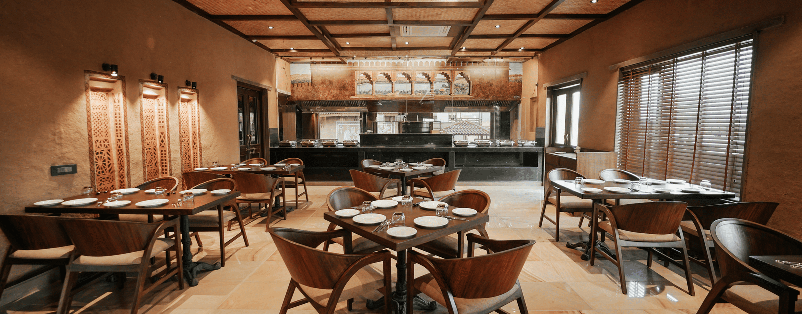 A spacious dining area at Aamaghati Wildlife Resort featuring elegant wooden interiors, stylish ceiling lights, and neatly arranged tables for a fine dining experience.