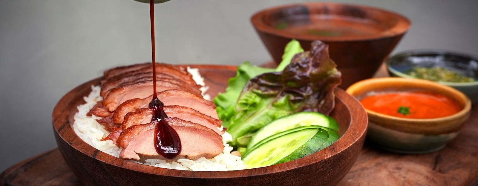 sauce being poured on Hainanse Duck with dip on the side at Village 36