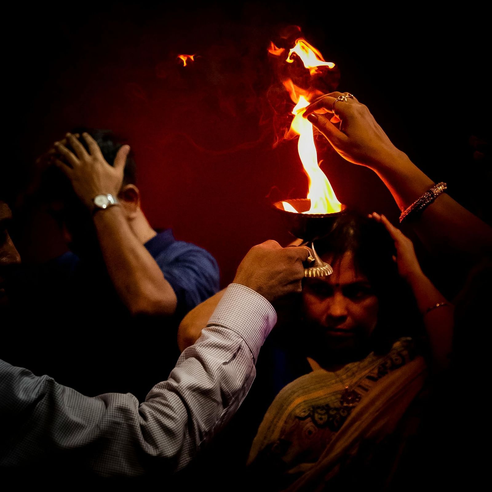 Devotees taking blessings from a flame during a prayer ceremony
