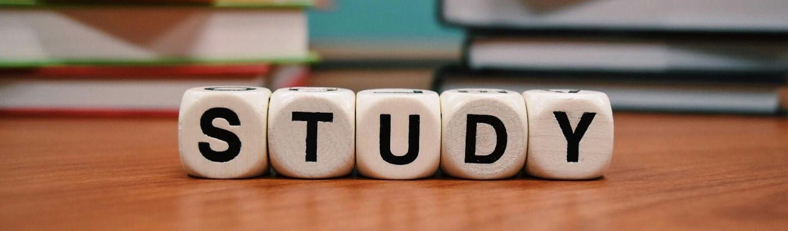 Shot features the word STUDY spelled out in white block letters, set against a blurred background of stacked books.